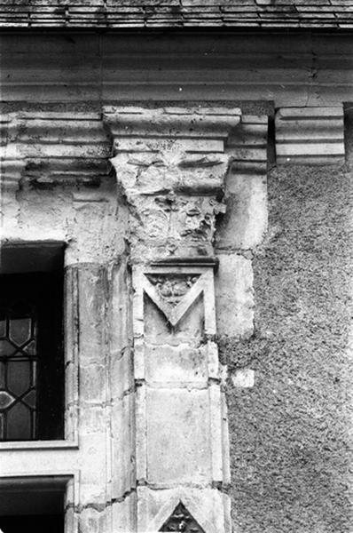 Façade nord sur cour, aile sud, fenêtre de droite du deuxième niveau, détail du pilastre droit surmonté d'un chapiteau.