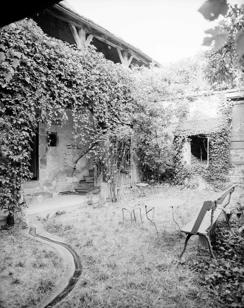 Façade sud sur jardin et puits contre le mur de clôture.