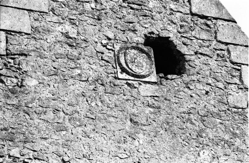 Ancienne chapelle : façade occidentale, pignon nord extérieur, détail blason entouré d'une guirlande et d'une inscription.