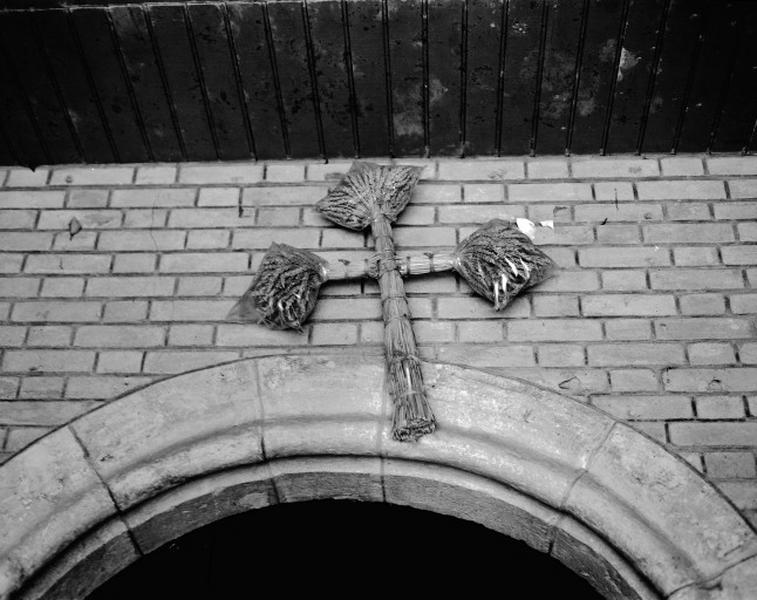 Façade ouest, au-dessus du portail, croix de procession pour la moisson.