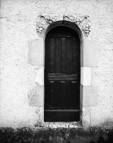 Porte d'accès de l'extérieur de la sacristie, façade nord, porte à simple vantail et linteau décoré d'une guirlande de fruits et fleurs.