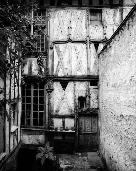 Façade postérieure sur cour du deuxième corps de logis ; le vantail de la porte est découpé en panneaux à décor renaissance ; les écus bûchés des deux panneaux supérieurs latéraux sont surmontés de couronnes fleurdélisées sculptées, vue d'ensemble.