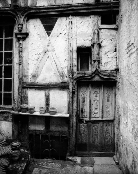 Façade postérieure sur cour du deuxième corps de logis ; le vantail de la porte est découpé en panneaux à décor Renaissance ; les écus bûchés des deux panneaux supérieurs latéraux sont surmontés de couronnes fleurdélisées sculptées, vue d'ensemble.