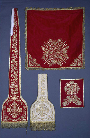 Ornements brodés rouge et blanc. Voile de calice : 59 x 61,5 ; bourse : 25 x 30 cm ; manipules : 26, étoles : 27, 5 cm.