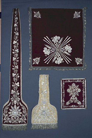 Ornements brodés violets et blanc. Voile de calice : 82 x 60 cm ; bourse : 26 x 31 cm ; manipules : 26, étoles : 25