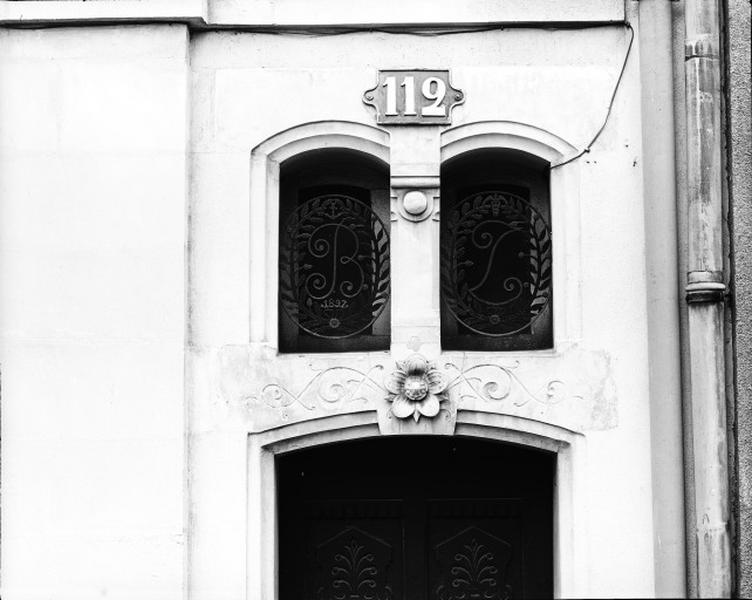 Façade antérieure, élévation, rez-de-chaussée, porte d'entrée, imposte, détail : fer forgé, initiales B et L, 1897, surmontées des symboles de la marine et de la pharmacie.