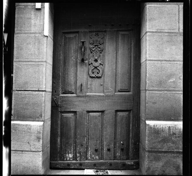 Porte d'entrée en bois, décor au centre en relief.