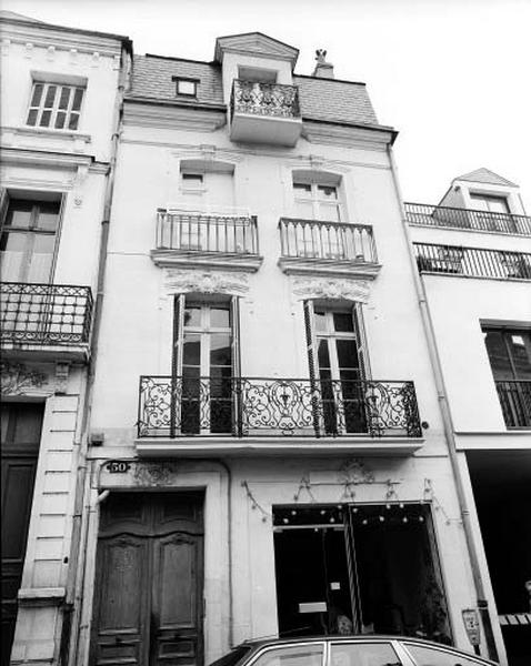 Façade sur rue, baies et porte décorées de motifs végétaux.