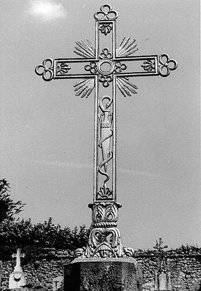 Cimetière : vue de détail de la croix de cimetière ornée d'un caducée et d'un masque de pleurant.