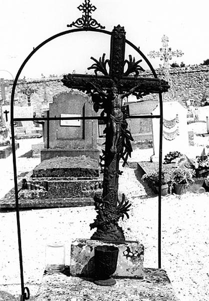 Cimetière : vue de détail d'une croix avec Christ, ornée d'épis de blé, de fleurs et de noeuds (1909).