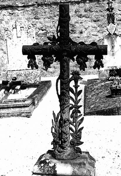 Cimetière : vue de détail d'une croix ornée de roses, de lys et de joncs (1926).