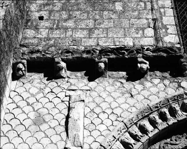 Détail de la façade, à gauche, avant restauration : appareil en écailles de poisson et modillons sculptés