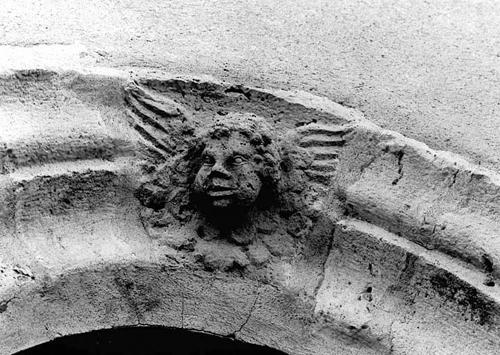 Vue de détail de l'angelot sculpté sur l'arc de la baie nord de la façade ouest.