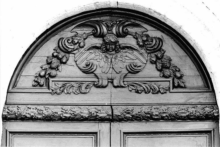 Vue de détail du tympan en bois de la porte.