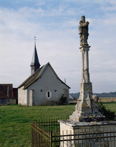 Ancienne église, actuellement propriété privée, prise de l'est. Au premier plan, une croix monumentale du XVe siècle qui se trouvait à l'origine dans le bourg de Bussy.