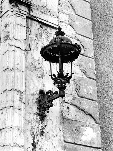 Vue de détail de l'un des lampadères muraux de la travée centrale de la façade principale nord-ouest, de l'est.