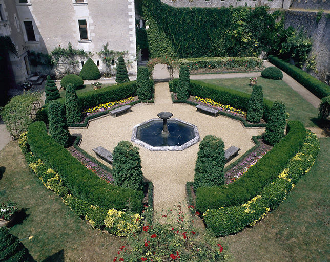 Le jardin 'médiéval', détail : une fontaine au centre d'un bassin est bordée par des allées où sont installés des bancs.