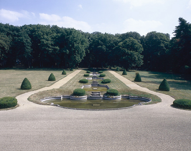 L'escalier d'eau vu depuis la grande salle du 1er étage : des ifs taillés ponctuent chaque gradin. L'eau semble venir du parc. Au fond la composition s'achève dans un hémicycle de rododhendrons.