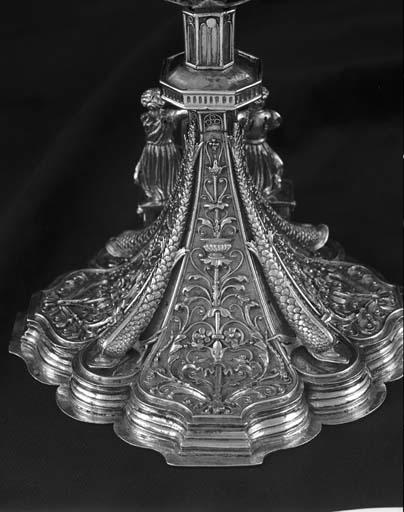 Détail du pied : décoration végétale et dauphins.