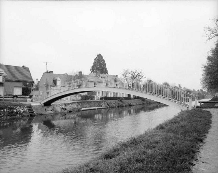 Passerelle courbe et lavoir au premier plan.