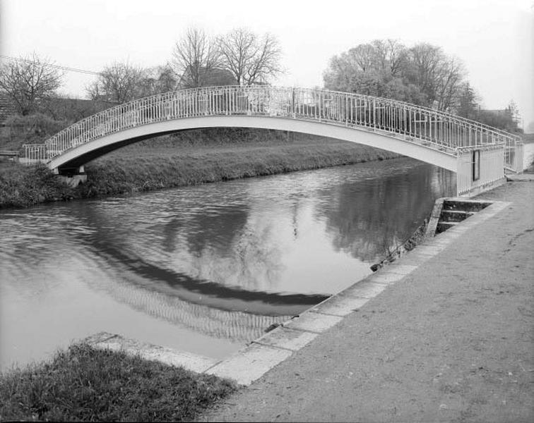 Passerelle courbe et lavoir au fond.