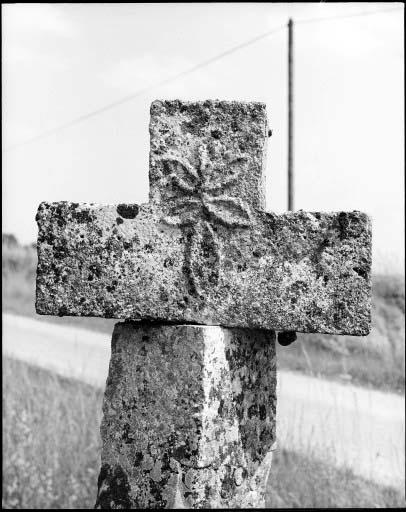 Croix de chemin en pierre avec inscription. Détail de la fleur sculptée.