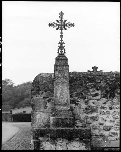 Vue d'ensemble d'une croix de chemin en fonte à l'angle du cimetière.