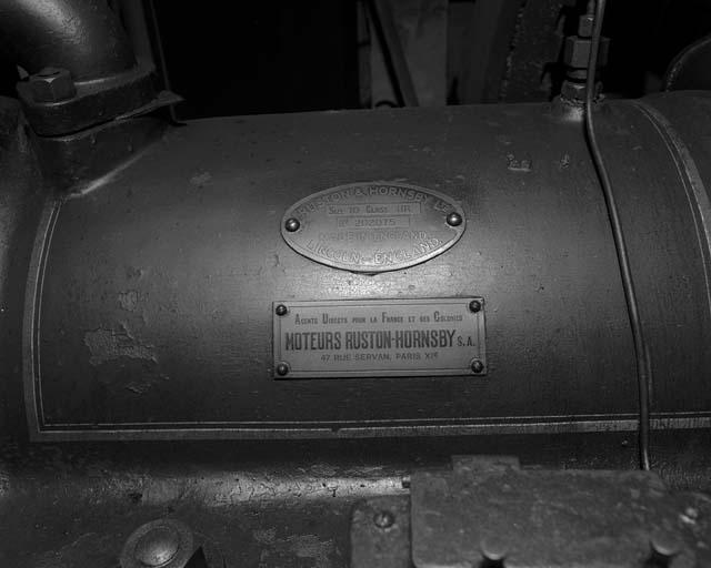 Le moteur diesel, plaques de constructeur et d'importateur : RUSTON et HORNSBY Ltd / SIZE 10 CLASS HR / No 202075 / MADE IN ENGLAND. / LINCOLN - ENGLAND. (sur une plaque ovale). AGENTS DIRECTS POUR LA FRANCE ET SES COLONIES / MOTEURS RUSTON - HORNSBY S.A. / 47 RUE SERVAN, PARIS XIe (sur une plaque rectangulaire).