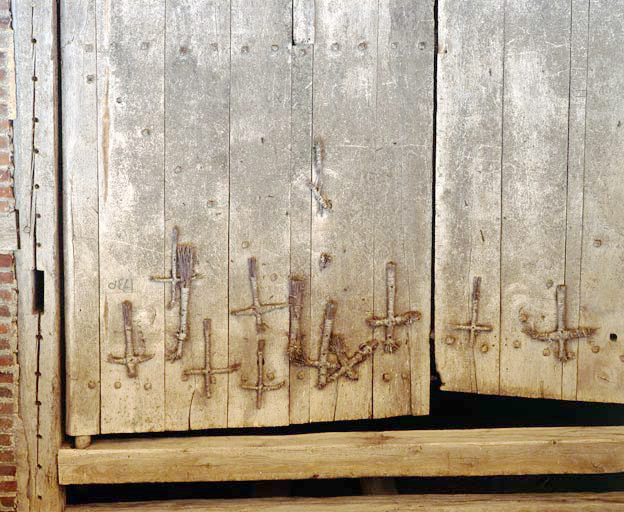 Détail de la porte de grange : date gravée (1730) et croix de paille accrochées au moment des moissons après avoir été bénies à l'église.
