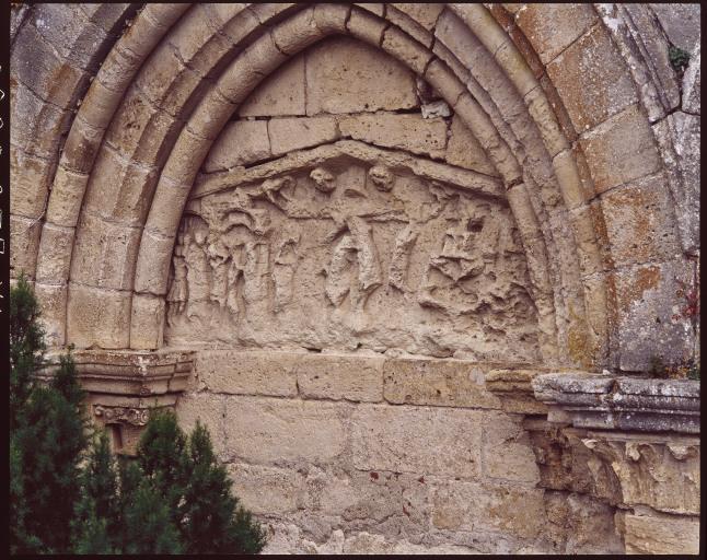 Eglise, façade ouest. Linteau en bâtière remployé dans l'arcade aveugle de gauche : Jugement du Christ chez Pilate, Descente de croix et Mise au tombeau.