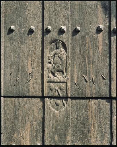 Détail d'une figure sculptée et d'un blason du vantail occidental.