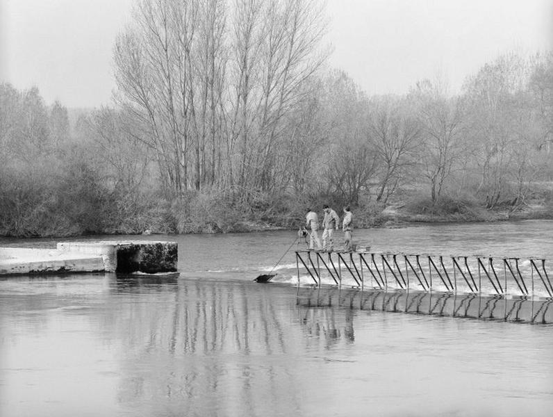 Relevage du barrage ; Cette manoeuvre consiste à relever la structure métallique du barrage (les fermettes) couchée au fond de la rivière et s'effectue au printemps.