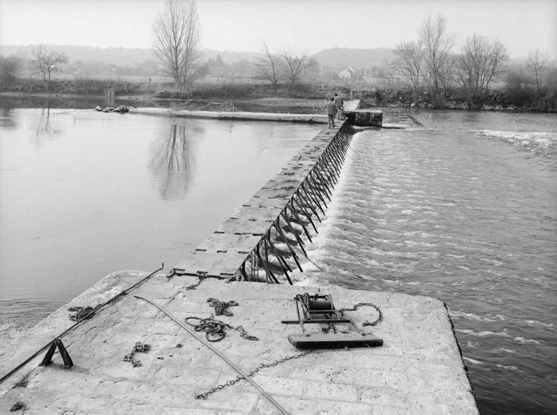 Relevage du barrage ; au premier plan, les crochets qui permettent de tirer les fermettes couchées au fond de l'eau et le treuil mobile qui se fixe sur le tablier du barrage.