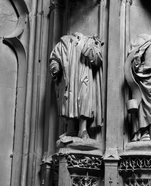 Contrefort de jonction entre la quatorzième et la quinzième travées nord, étage inférieur, statuette gauche : homme vêtu d'une esclavine et d'un manteau attaché sur l'épaule gauche. La tête et les mains ont disparu.