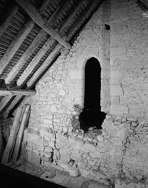 Vue intérieure du comble. Face externe d'une porte en arc brisé de l'édifice médiéval.