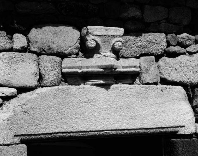 Façade antérieure. Porte d'entrée. Détail d'un chapiteau à crochets et d'une base de faisceau de colonnes en remploi.