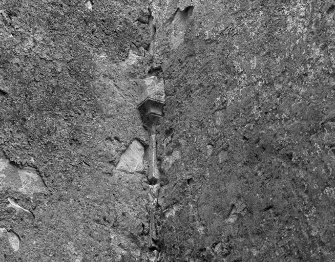 Vue de détail d'un vestige de maçonnerie noyé dans dans l'angle des murs de la nef et du croisillon nord.