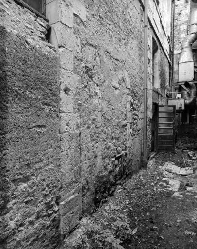 Baie géminée romane bouchée au rez-de-chaussée de la façade ouest du corps de bâtiment perpendiculaire à la collégiale.