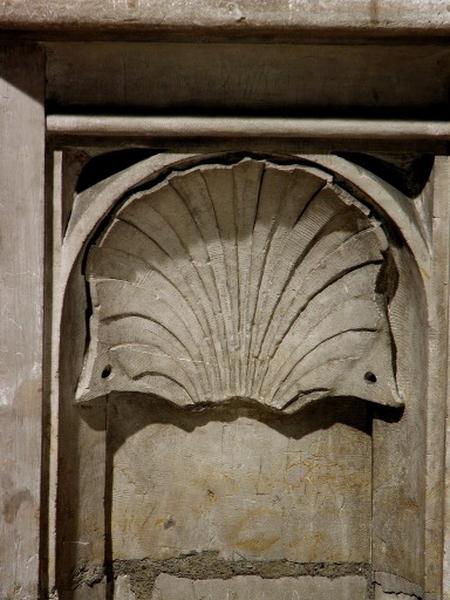 Troisième travée sud, soubassement de la quatrième section, coté droit : motif de coquille ouverte dans un arc en plein-cintre dont les coins inférieurs développés sont percés d'un trou (vue rapprochée).