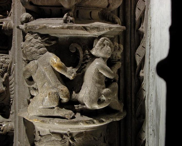 Quatrième travée sud, colonne-candélabre de la première section, retour droit : deux petits personnages en haut-relief sculptés de dos, à gauche un satyre tenant une corne d'abondance et à droite une ménade nue portant un vase de fruits.