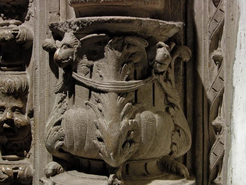 Quatrième travée sud, colonne-candélabre de la première section : vase à pieds orné de feuilles d'acanthe et de têtes de fauves ailés tenant dans leur gueule des anneaux reliés par un ruban (vue rapprochée).