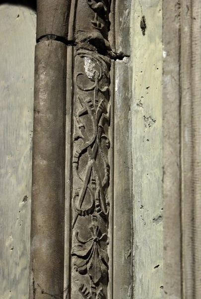 Quatrième travée sud, claire-voie de la première section, premier meneau : détail de la chute d'objets, instruments du rôtisseur entrecroisés entre deux bouquets de fleurs.