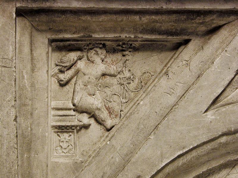 Onzième travée nord, première section, médaillon gauche, écoinçon supérieur gauche : putto assis sur une stèle, un rapace sur la main droite, tenant dans l'autre main un sceptre sur lequel est accroché un cartouche portant la date 1527. Sur la stèle figure une Sainte Chemise de la Vierge.