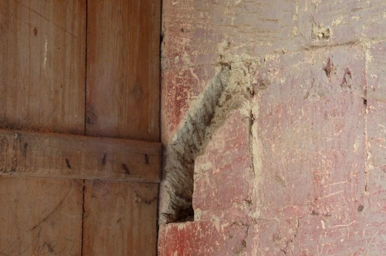 Grande salle du logis seigneurial. Détail du mur près d'une baie avec emplacement d'un système de fermeture.