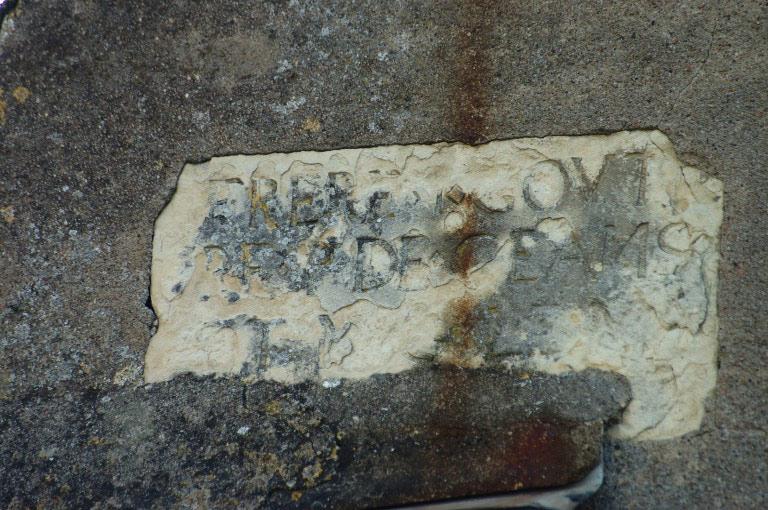 Plaque, avec inscription partiellement visible sise 19 rue de Chambord, provenant sans doute du cimetière qui entourait l'église avant la Révolution.