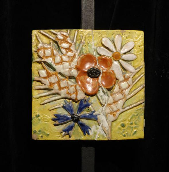 Plaque ornée d'épis de blé et de fleurs des champs.