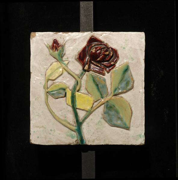 Plaque ornée d'un bouton et d'une rose rouges.