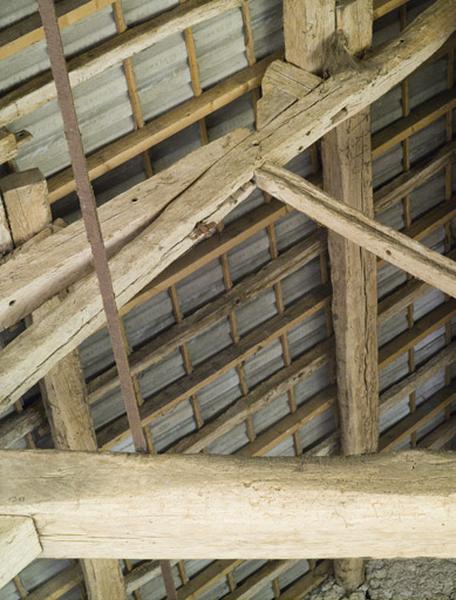 Clavette d'un boulon enserrant l'arbalétrier d'une ferme avec une pièce de bois qui le prolonge.
