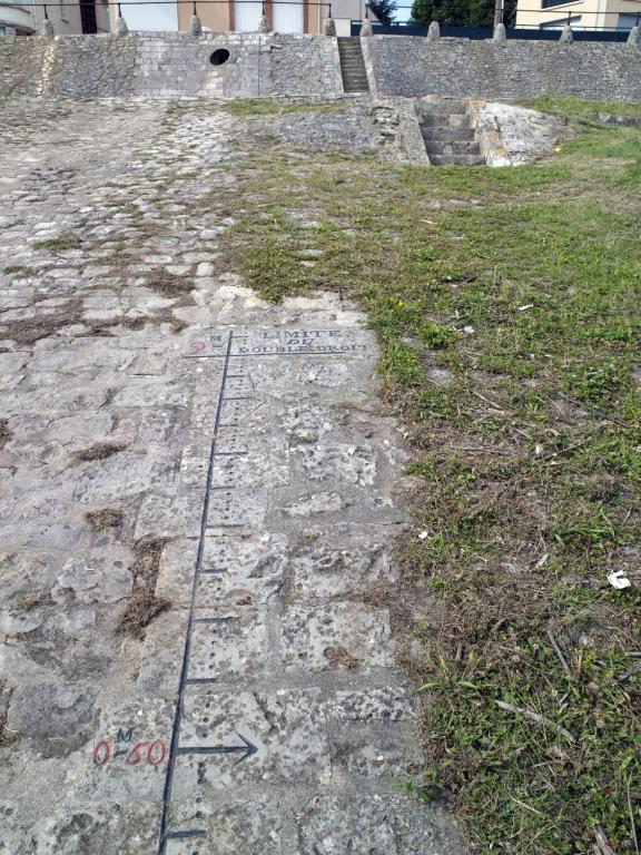 Limite du double droit gravé sur le pavage du port, en amont du pont. Lorsque l'eau dépassait la cote de deux mètres, le prix du passage en bac était multiplié par deux.