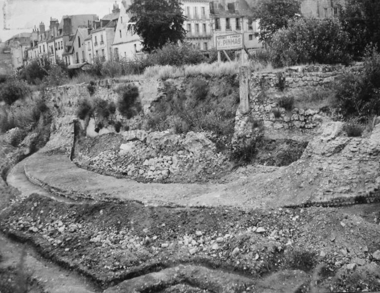 Vue des ruines du temple découvert lors des fouilles de l'îlot, depuis la rue Nationale, [1952]. (archives départementales d'Indre-et-Loire, Fonds Arsicaud 5 Fi P128, cliché n°8277-4).